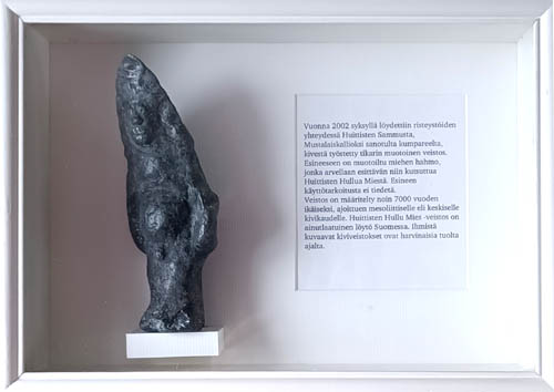 Paperimassasta tehty kivikautista esinettä muistuttava veistos vitriinissä.